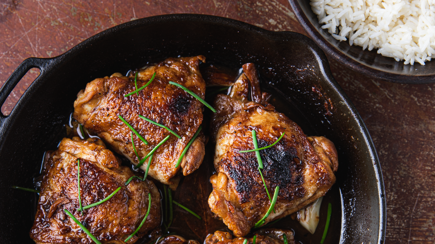 Chicken Adobo in a cast iron pan served next to white rice. recipe poster image